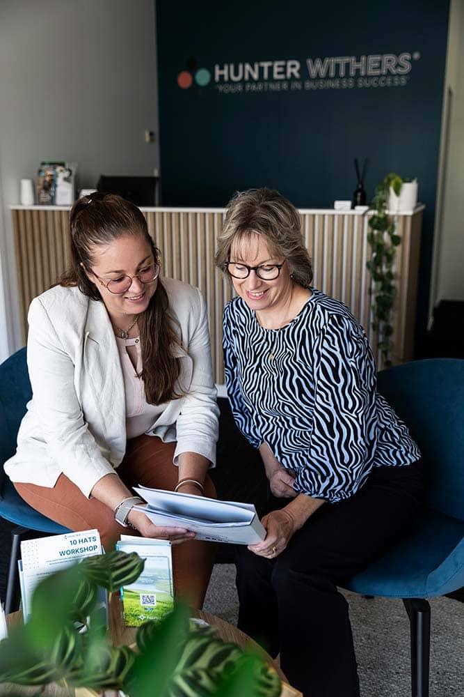 Brigette, Director at Hunter Withers, reviewing a folder with a team member in the front reception area of the Pukekohe accounting office.
