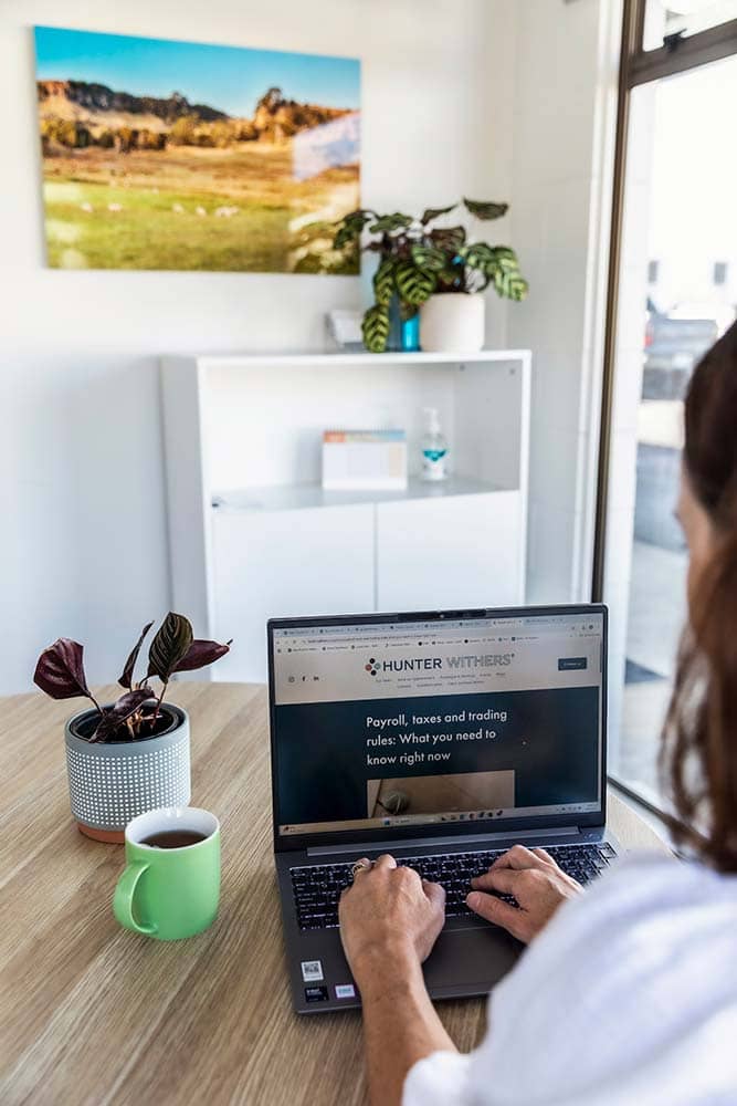 Over-the-shoulder view of a Hunter Withers staff member working on a laptop at the Pukekohe accounting office.