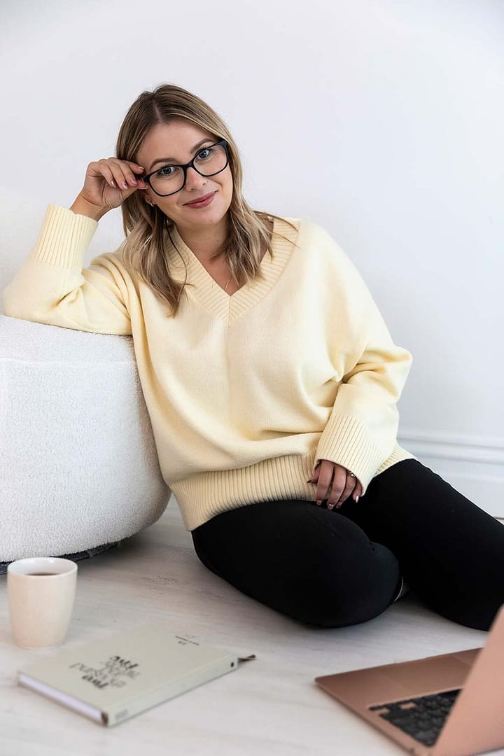 Emma Bracken lounging comfortably on her living room floor with a hot drink, 2025 planner, and laptop within reach, blending warmth and productivity in a homey setting.